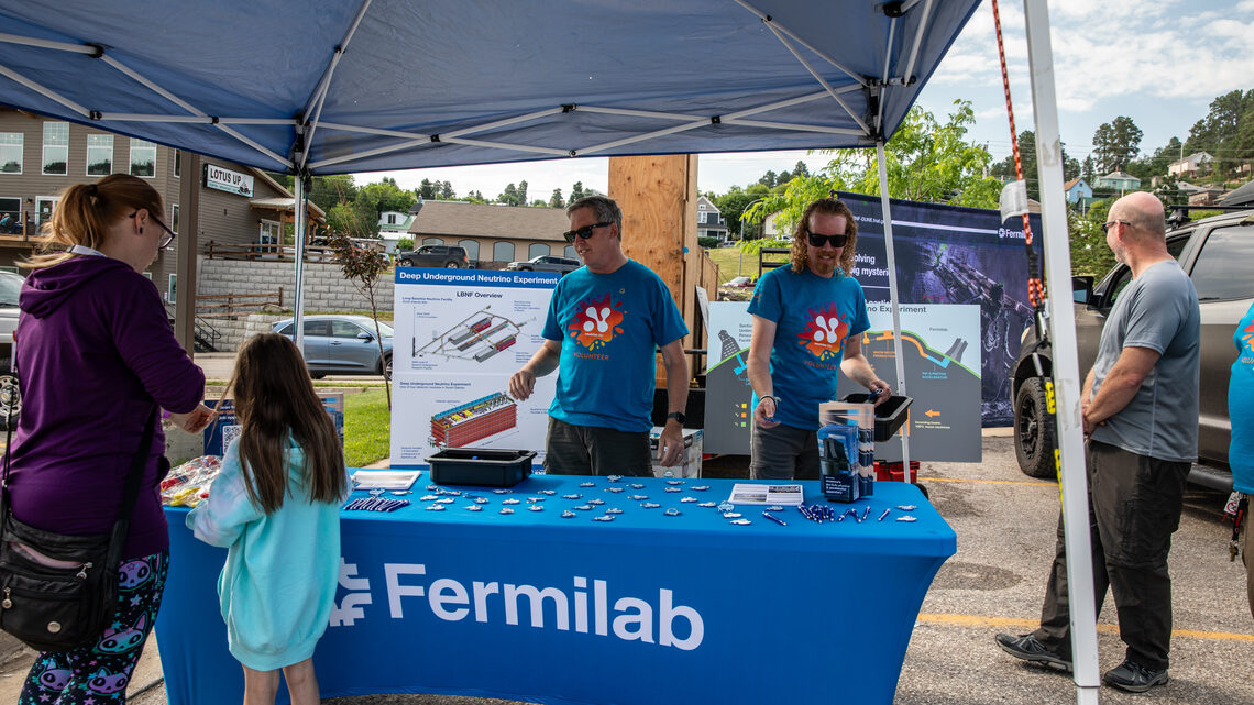 The tent for Fermilab at Neutrino Day was a popular place for many. Participants are gathered around the fermilab tent.
