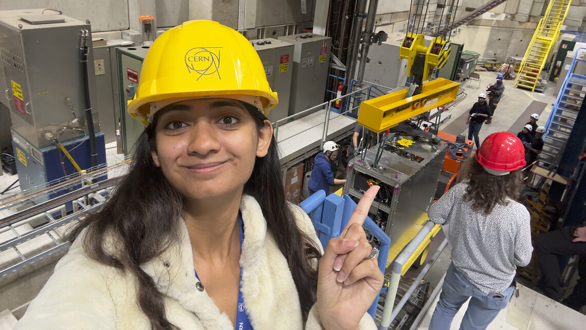 Woman in hard hat points to a crane in the background