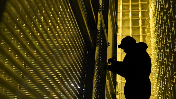 Silhouette of a person working in a golden-hued room.