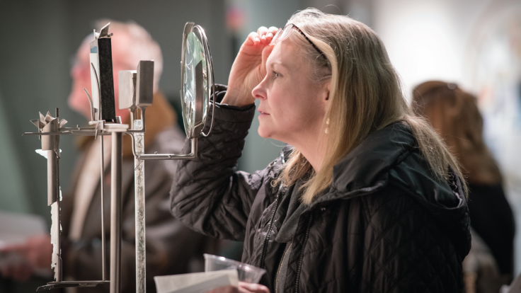 At the artist’s reception for Jenkins’ show, a visitor peers through the magnifying glass of a sculpture called The Wait of the 